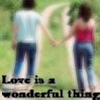 Two people holding hands while walking away from the viewer on a grassy path with blurred green background.
