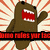 Brown pixelated character with wide red mouth and raised arm against striped background, next to brown device displaying text.