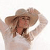 A pixelated figure wearing a wide-brimmed straw hat and light-colored shirt, hands raised to adjust the hat against a plain white background.