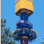 A pixelated static image shows a blue cylindrical structure with layered segments, topped by a yellow rounded cap and brown base against a light blue background.