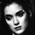 Black-and-white pixelated image of a person's face with dark hair, visible eyebrows, nose, mouth, and eyes, set against a dark background.