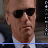 showing a man in a dark suit and white shirt with black sunglasses, vertical purple text reading "Perfection" on the right side