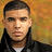 Pixelated portrait of a person with short dark hair wearing a dark jacket over a light shirt against a warm-toned gradient background.