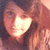 Pixelated image of a person with light brown hair and a bright heart-shaped light effect over their face, set against a dark background.