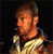 Pixelated close-up of a person with short brown hair wearing a light-colored shirt against a dark background.