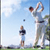 Pixelated static image of two golfers on a course with one mid-swing and another watching, set against a blue sky background.