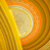 A pixelated circular icon with a central light beige area surrounded by concentric rings of orange and yellow hues, set against a checkered background.