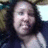 Pixelated static image of a person with dark hair and light skin, wearing a white top against a blurred background.