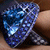 Blue and silver pixelated ring with reflective surface held between fingers, showing subtle animation changes