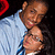 Two pixelated figures in close physical proximity, one wearing a light blue shirt with dark stripes on the sleeves against a black background.