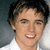 A person with short dark hair and a white shirt smiles broadly across three showing slight head movement