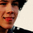 Pixelated close-up of a person's face showing a broad smile, dark hair, and dark clothing against a light background.