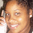 A static pixelated image shows a person with light brown skin smiling, holding a white object near their face, with dark hair visible on the right side of the frame.