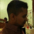 Pixelated static image of a person with short dark hair, side profile, wearing a dark shirt against a light background with indistinct shapes.