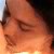 Pixelated close-up of a person's face showing closed eyes, nose, and mouth with warm orange and brown tones against a light background.