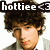Pixelated image of a person with dark curly hair and light skin, wearing a gray jacket over a white shirt, with text overlay reading 'hottie' in white letters on black background.