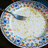Circular icon with colorful pixelated border showing a spoon stirring white liquid in four