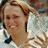 Static 48x48 pixel icon showing a smiling person with light brown hair wearing a white shirt and dark tie, set against a blurred background with indistinct shapes.