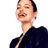Pixelated static image of a person with short dark hair wearing a dark top, smiling broadly with eyes closed and mouth open showing teeth against a white background.