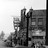 Black-and-white pixelated image of a building with multiple windows and a tall central tower-like structure against a light background.