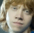 Pixelated close-up of a person with light brown hair and fair skin, showing partial facial features against a blurred background.