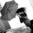 Pixelated grayscale image of two figures in close physical proximity with one figure's hand near the other's face.