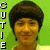 A person with short dark hair and earrings appears in three against a green background, with text "CUTIE" on the left