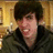 Pixelated image of a person with dark hair in a dimly lit room, accompanied by blue text reading "RAW!" and "Kevin's My Little Baby Dinosaur!" on black background.