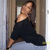 A pixelated image shows a person in dark clothing lying on the floor with legs spread, against a wooden door and light-colored wall.