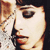 A pixelated close-up of a person's face with light skin, dark hair, and red lips, partially obscured by a blurred background element.