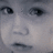 A split-screen image with a grayscale close-up of a child's face on the left and pink background text on the right.
