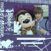 Mickey Mouse in brown jacket and white gloves waves with right hand while standing next to a person in blue shirt against purple background with white text and graphics.