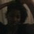 A pixelated static image shows a person with dark hair and light skin, wearing a white shirt against a dark background.