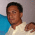 A static pixelated image shows a person with short dark hair wearing a light-colored shirt, positioned against a gray background with a blue object on the left.