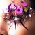 Pixelated static image of a stylized figure with large purple eyes and pink floral accents on the head, holding dark slender objects against a blurred background.