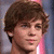 Pixelated close-up of a person with brown curly hair, light skin tone, and visible ear against blurred background.