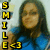 Pixelated image of a person with long dark hair wearing blue clothing, next to vertical yellow text reading 'SMILE' and a smiley face symbol.