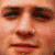 Pixelated close-up of a face with brown eyes, a nose, and a mouth, rendered in warm tones of orange and brown.