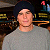 Pixelated static image of a person in gray clothing with dark hair, set against a background featuring yellow and blue elements including a red '1' symbol.
