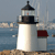 Static pixelated image of a white lighthouse with black trim and a red-roofed building beside it, set against a blue water and sky background.