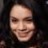 Pixelated close-up of a person's face with light skin tone, dark hair, and a neutral expression against a dark background.