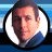 Pixelated circular portrait of a man with short dark hair against a blue gradient background, next to pixelated text reading 'ADAM SANDLER .COM' on a solid blue field.