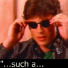 A person in a black jacket and green shirt adjusts dark sunglasses against a peach-colored background, with text overlays reading "...such a...", "blatantly", "aggressive", and "offspring.".