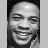 Pixelated grayscale image of a smiling person with closed eyes, dark hair, and a light-colored garment against a dark background.