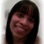 Pixelated portrait of a person with dark hair and a light background, showing a smiling expression with closed eyes.