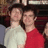 Two people stand side-by-side in a pixelated image; one wears a light-colored shirt, the other a red shirt.