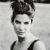 Black-and-white pixelated image of a person with short dark hair styled upward, wearing a sleeveless top with dark straps, against a light background.