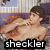 Pixelated image of a shirtless person with brown hair lying on their side, facing left, against a blurred background with blue and orange tones.