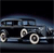 Pixelated image of a dark-colored sedan with visible headlights, wheels, and side mirrors against a dark background.
