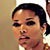 Static pixelated close-up of a person's face with dark hair tied back, visible in low-resolution 50x50 icon format.